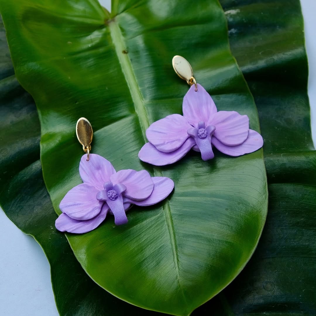 Purple orchid drop earrings with gold oval stud on tropical leaf